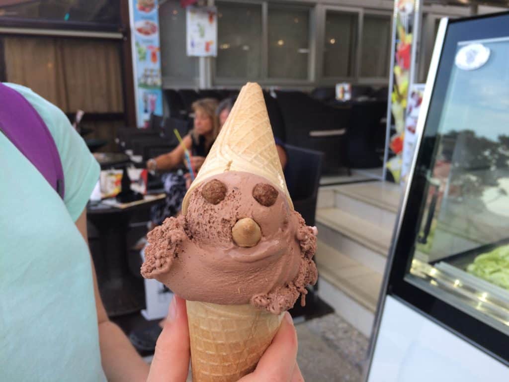 A fun ice cream made to look like a face with another cone on top as a hat